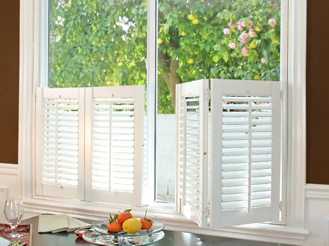 Café-style shutters covering the lower half of a window, with the glass above left open to the garden