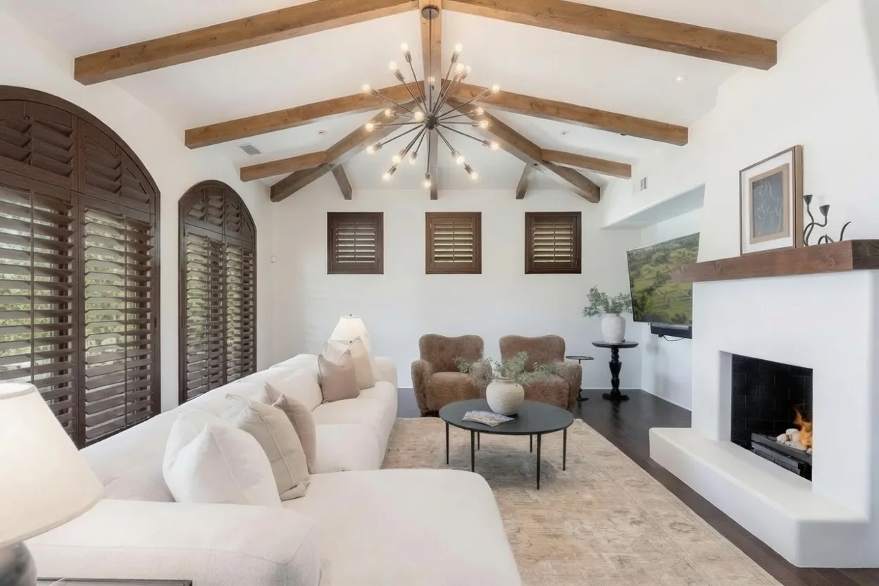 Stained wood arched shutters in a living room with exposed wood ceiling beams