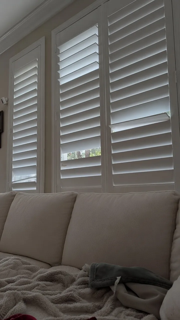An older wood shutter with louvers that have sagged and pulled loose from the panel