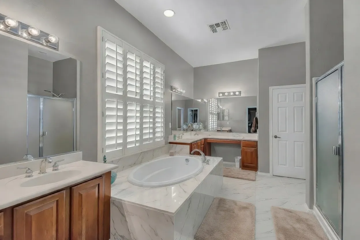 White composite plantation shutters over the garden tub in a primary bathroom in Anthem, Arizona